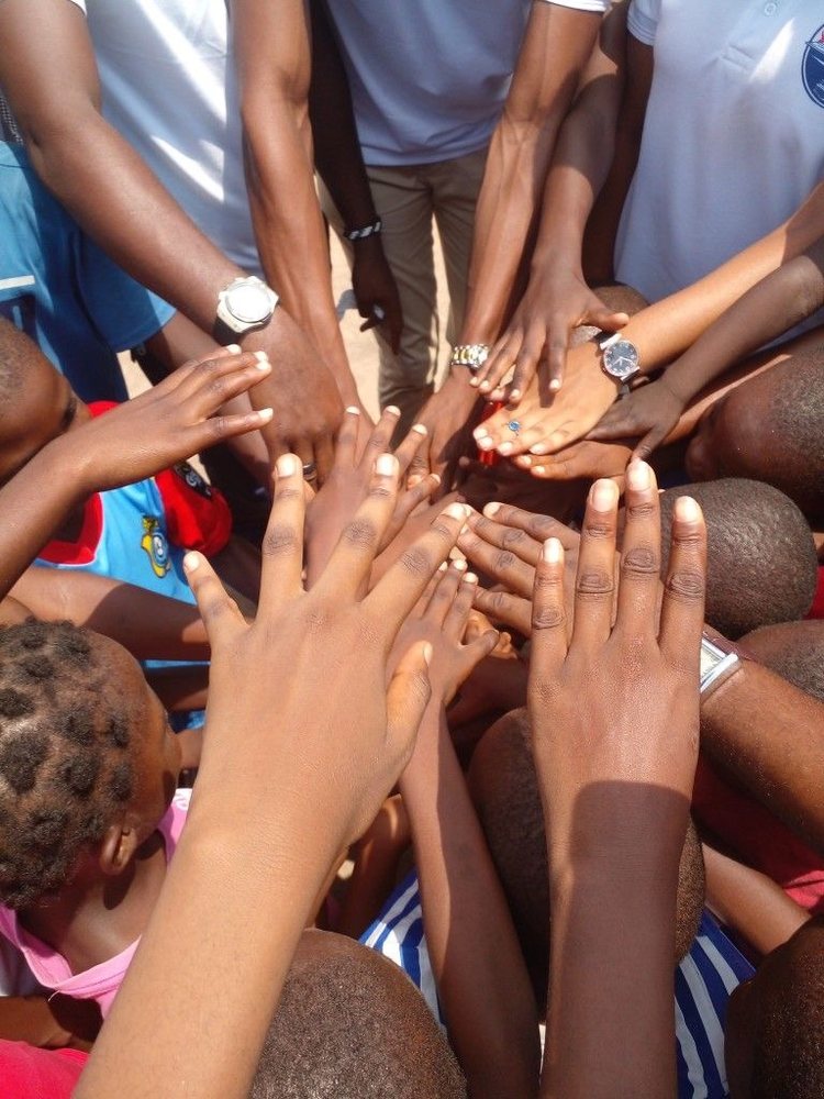 Mains d'enfants et de bénévoles réunies en cercle lors d'une action humanitaire